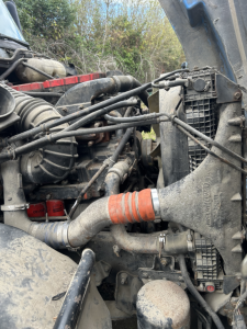 Truck engine bay of a Freightliner FC2 with hoses, radiator, and various components visible from side view.