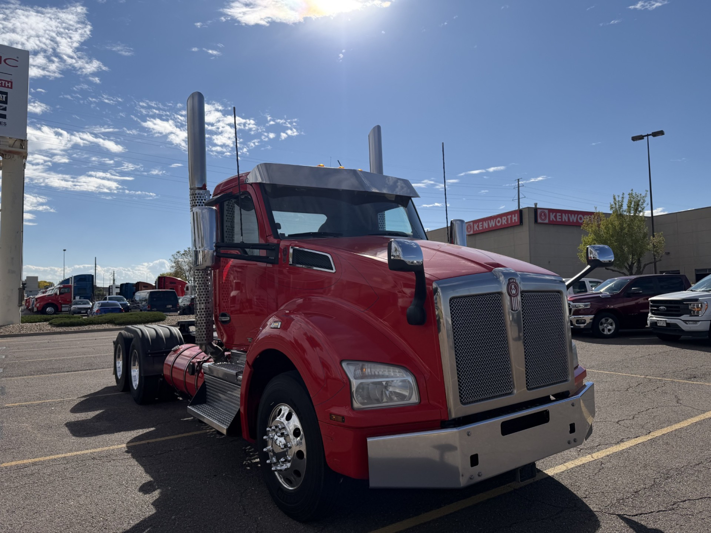Kenworth T880 conventional daycab truck in red, side view showing chrome grille, dual exhaust stacks, large front bumper.