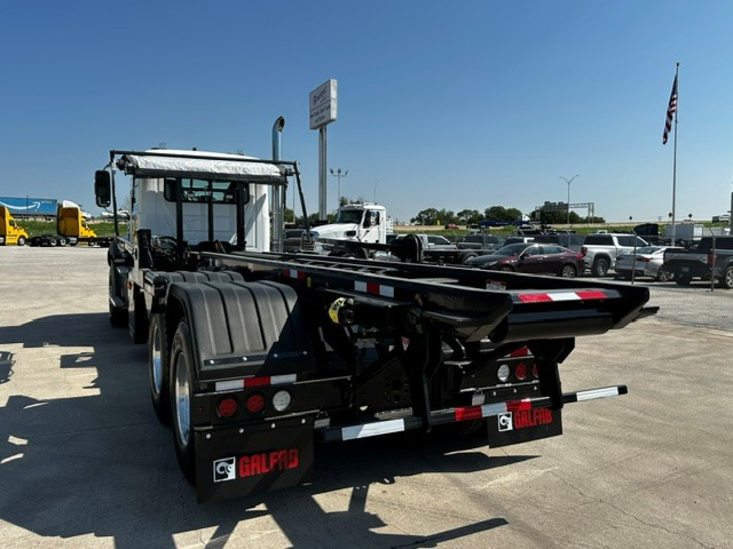 Rear view of a new 2027 Mack GR64B roll-off truck showing the rear body, mud flaps with GALF? branding, and the chassis with dual rear wheels.