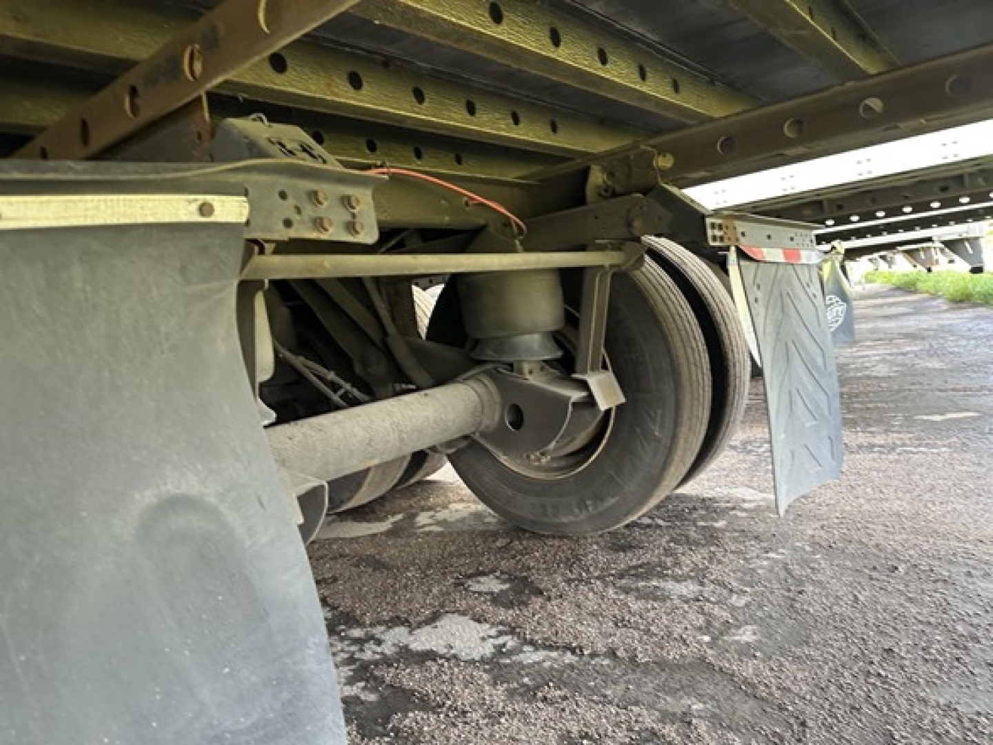 Trailer axle and wheel assembly undercarriage showing suspension and frame components