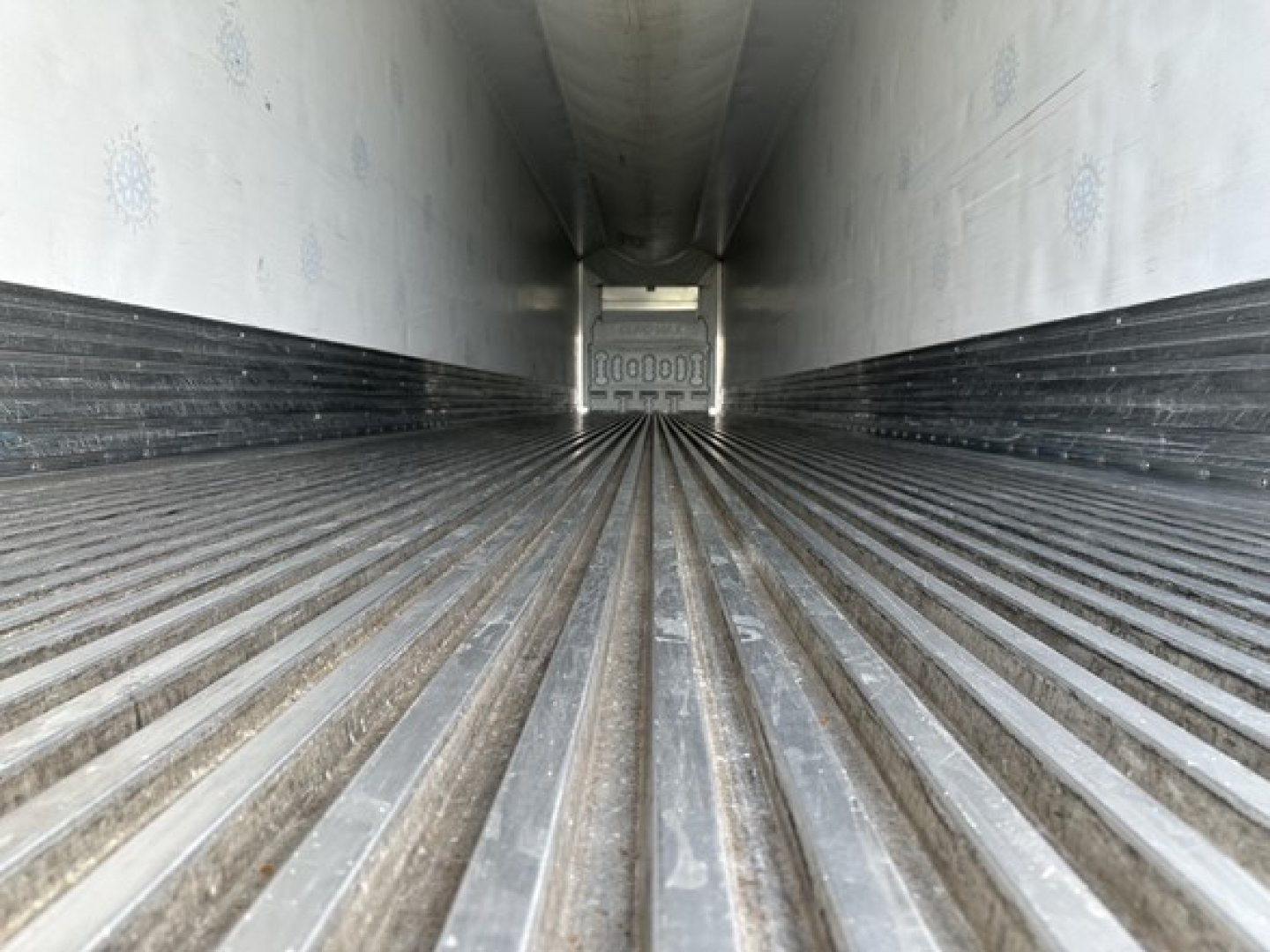 Trailer interior showing corrugated metal floor and side walls, long narrow cargo area with closed end doors visible in distance.