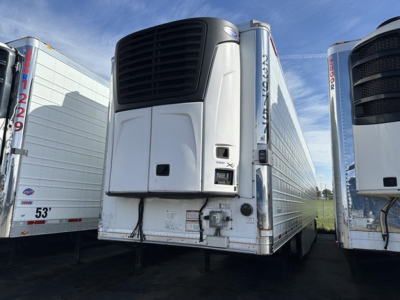 Carrier reefer trailer with front refrigeration unit and side doors, 7300 series, white with black grille, adjacent trailers.
