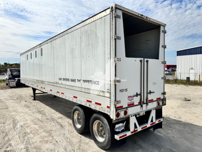 Trailer rear-right view showing aluminum chip trailer with open rear door, dual axles, and tail lights.
