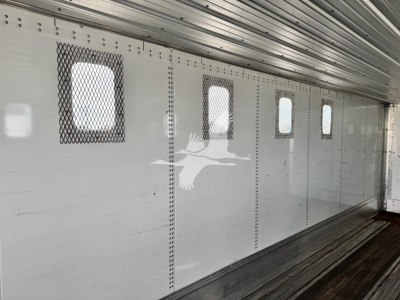 Trailer interior showing aluminum walls with small rectangular windows and ventilation grilles.