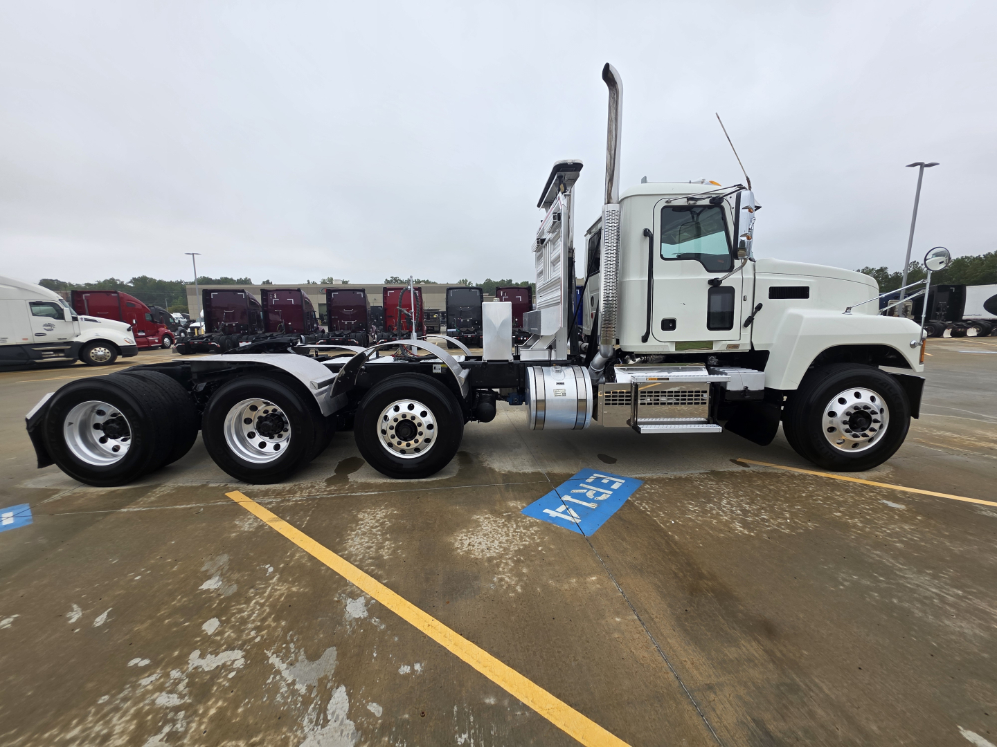 Mack Pinnacle 64T highway tractor side view showing white cab, attached chassis, dual rear axles, exhaust stack, and fuel tanks.