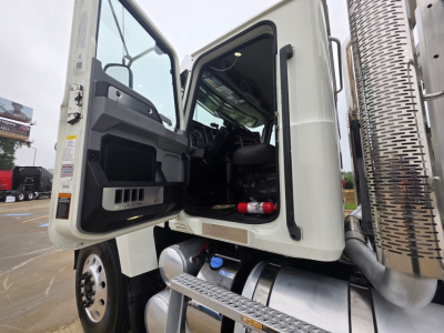 Truck cab interior visible through open door of a 2020 Mack Pinnacle 64T tractor with step, fuel tanks, and chrome exhaust stack.
