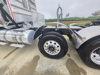 Mack Pinnacle 64T truck front axle and wheel well showing polished aluminum fuel tank, fender, and tire detail; VIN and stock number not visible in image
