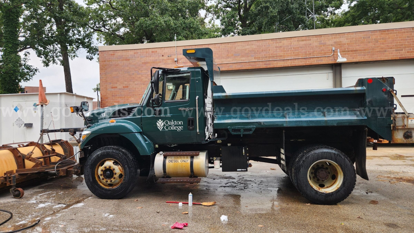 Truck bed view: green 2013 International 7400 dump truck with plow equipment, VIN 1HTWDAAR3DH466923, stock 13023-102, in-service vehicle.