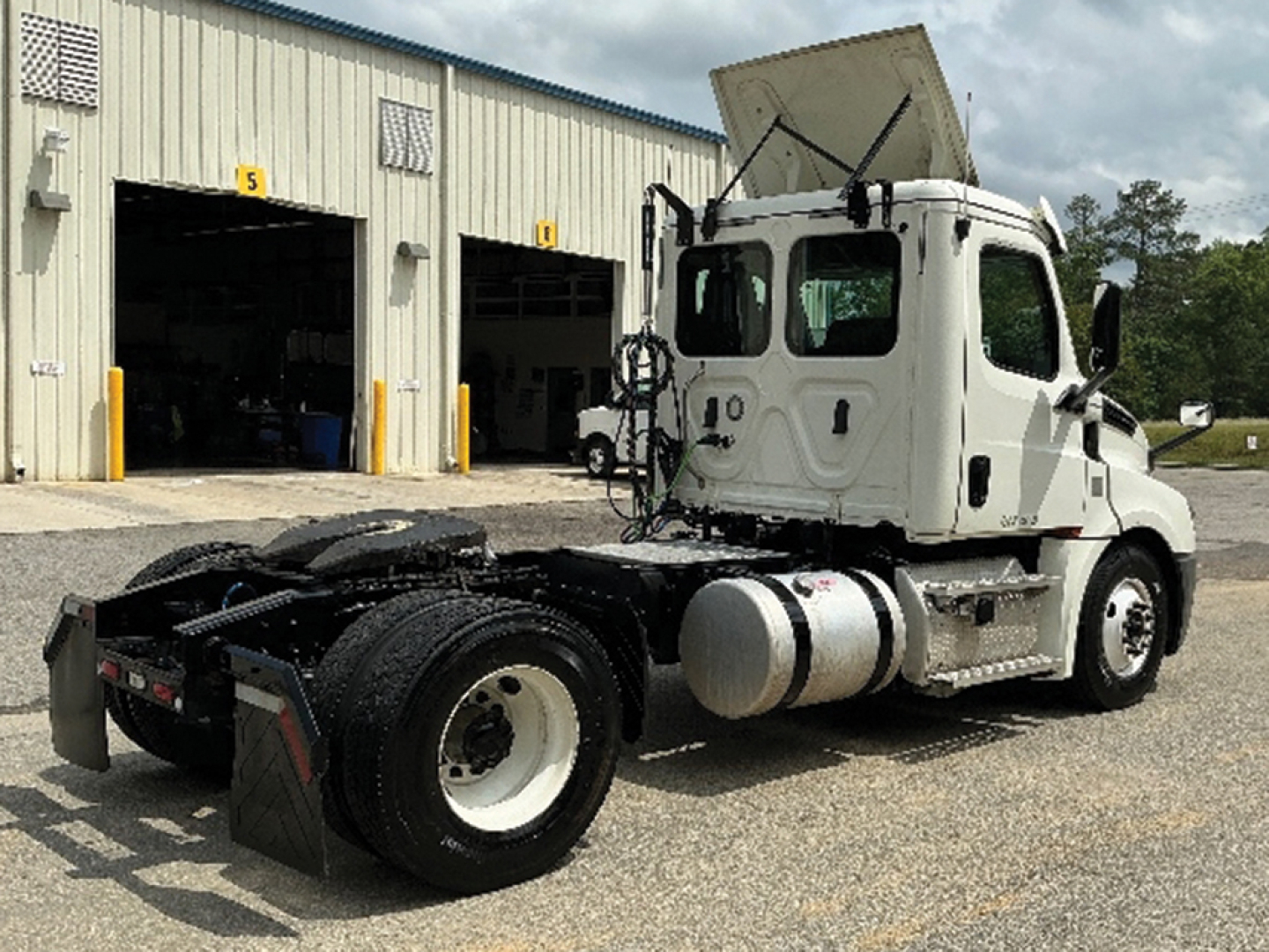 Truck chassis of a 2019 Freightliner Cascadia126 daycab with raised sleeper cabin, fuel tanks, and dual rear axles visible in a lot