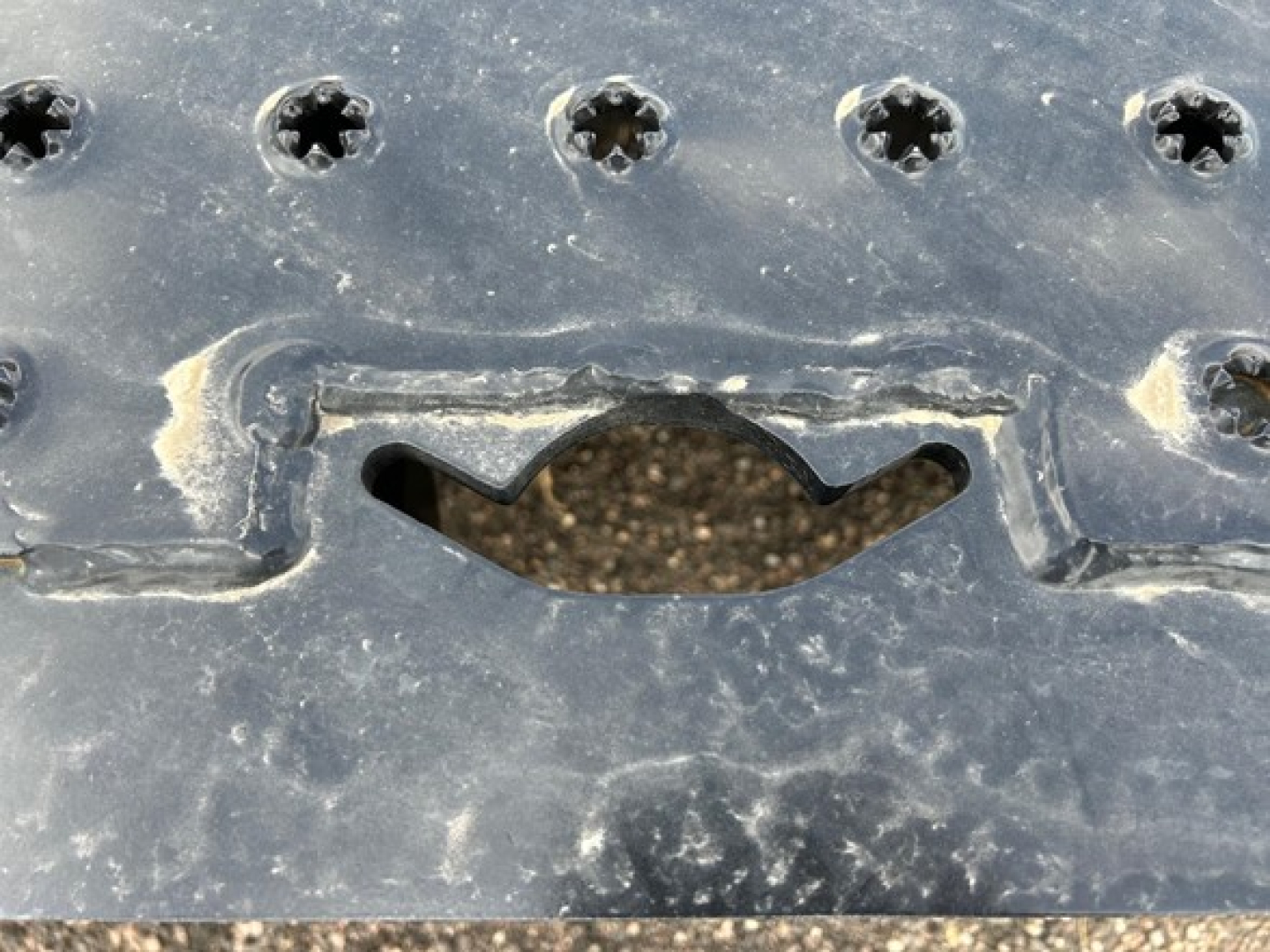 Trailer hitch area of a new Trail-Eze TE80Ht trailer showing metal surface with screws and a curved cutout near a hatch.