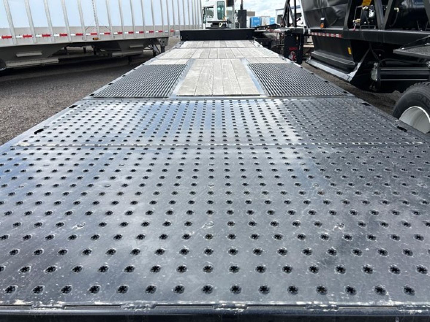 Trailers with perforated steel deck and central raised area, perspective view of a Trail-Eze TE80Ht flatbed trailer.