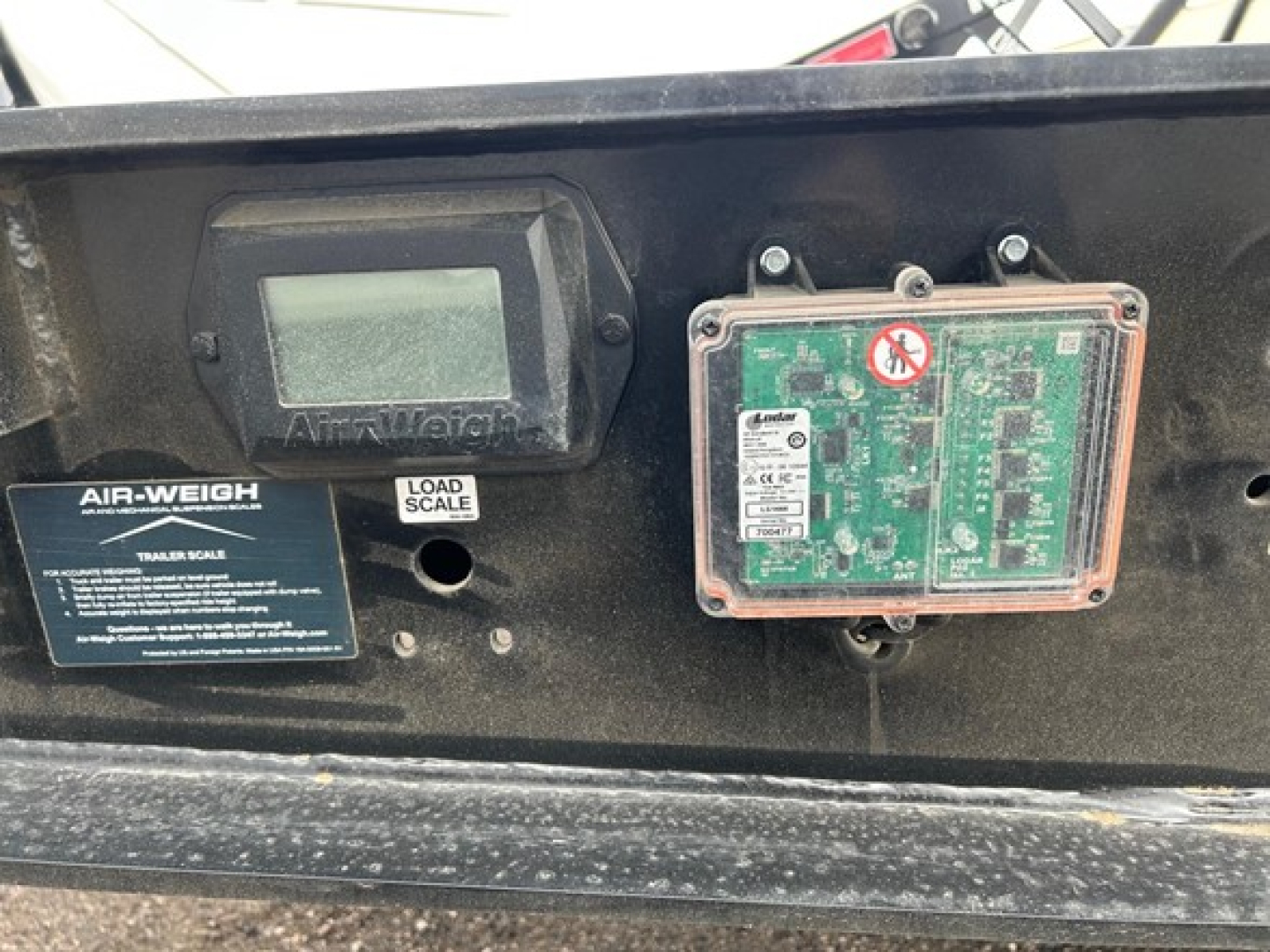 Trailer information panel showing AIR-WEIGH load scale indicator and a green control/diagnostic circuit board in a trailer front panel.
