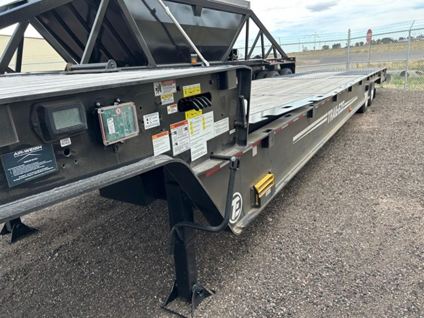 Trail-Eze TE80HT traveling trailer deck side with control panel and warning labels visible.