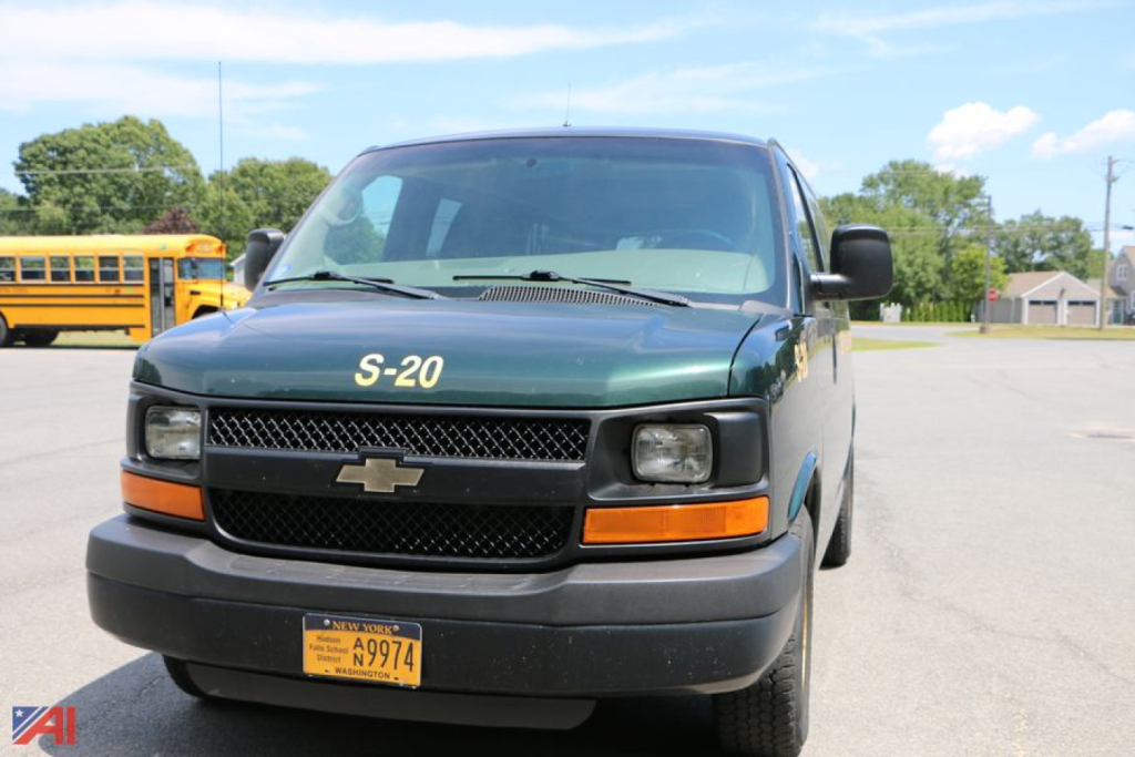 Chevrolet Express Passenger Van front view showing green body, black grille, amber turn signals, New York yellow license plate, S-20 decal on hood.