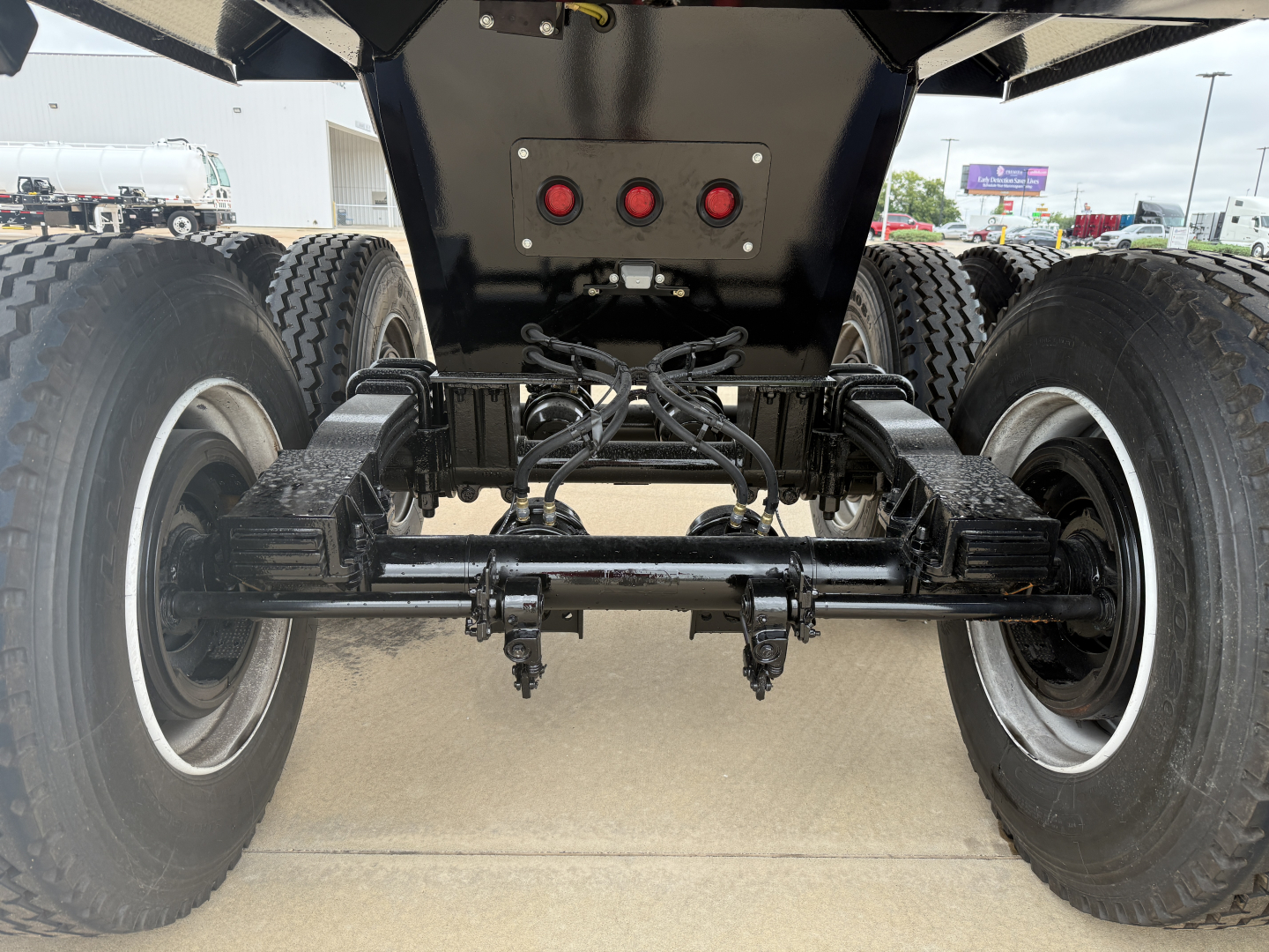 Armor Lite SHD32/48 trailer rear dual-axle suspension and wheels with black undercarriage components and hydraulic lines.