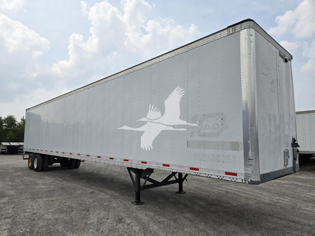 Trailer side profile showing a Vanguard logo and a long silver aluminum trailer with support legs extended, no visible license plates or occupants.