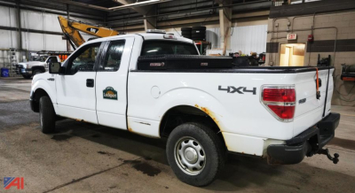 Ford F-150 extended cab 4x4 pickup truck with white paint, 2014 model, side badge visible, cargo bed and tow hitch in an indoor shop setting.