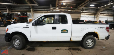 Ford F-150 Extended Cab 4x4 pickup truck in a warehouse setting, white with a tool bed, showing 'Lockport' decal around the door area.