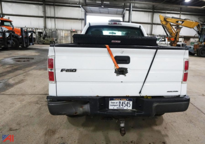 Ford F-150 extended cab pickup truck rear view showing tailgate with F-150 badge and license plate, in a workshop setting.