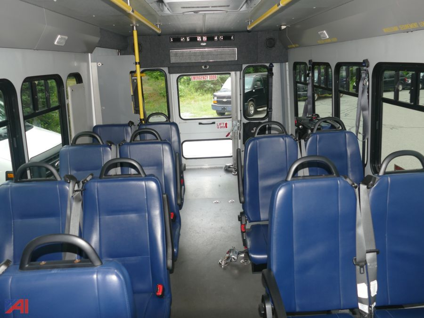 Bus interior with blue seating and wheelchair lift accessible rear area showing multiple rows of seats.