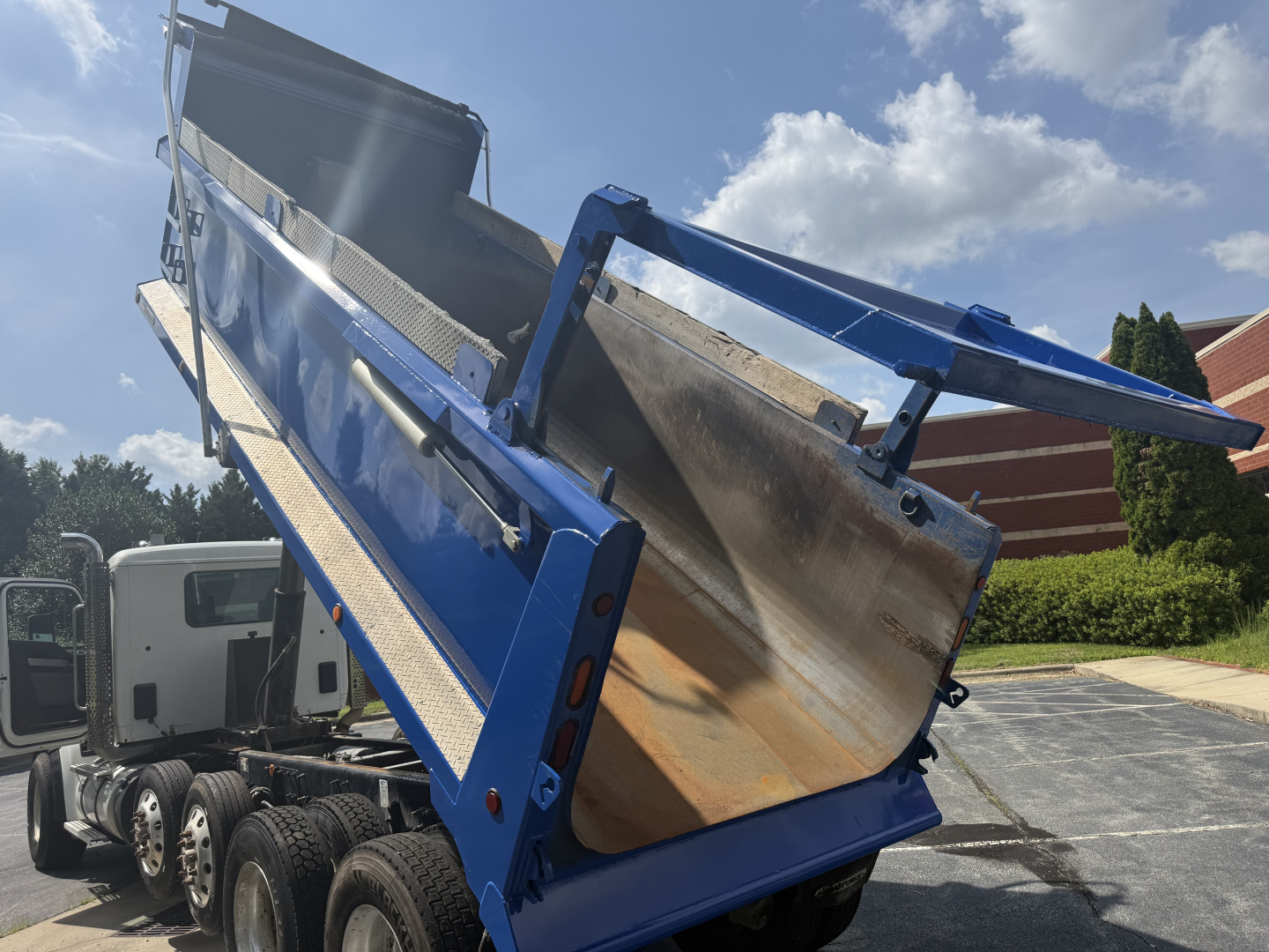 Kenworth T880S dump truck bed in a raised position showing blue dump body and hydraulic area.