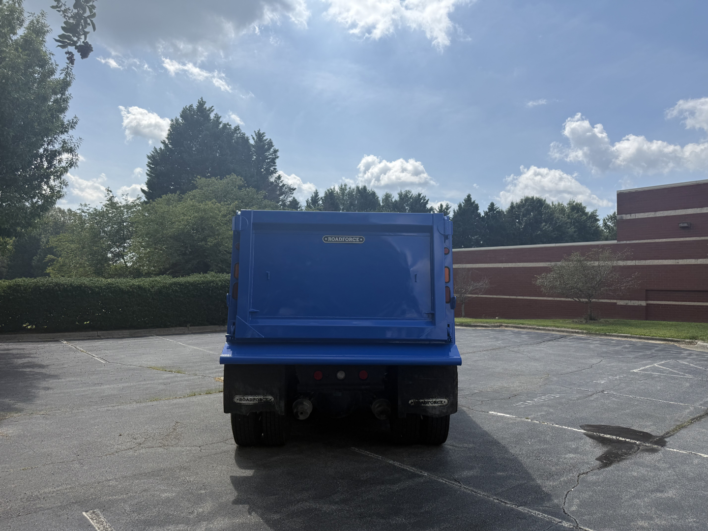 Kenworth T880S dump truck from rear view in a parking lot showing blue dump bed.