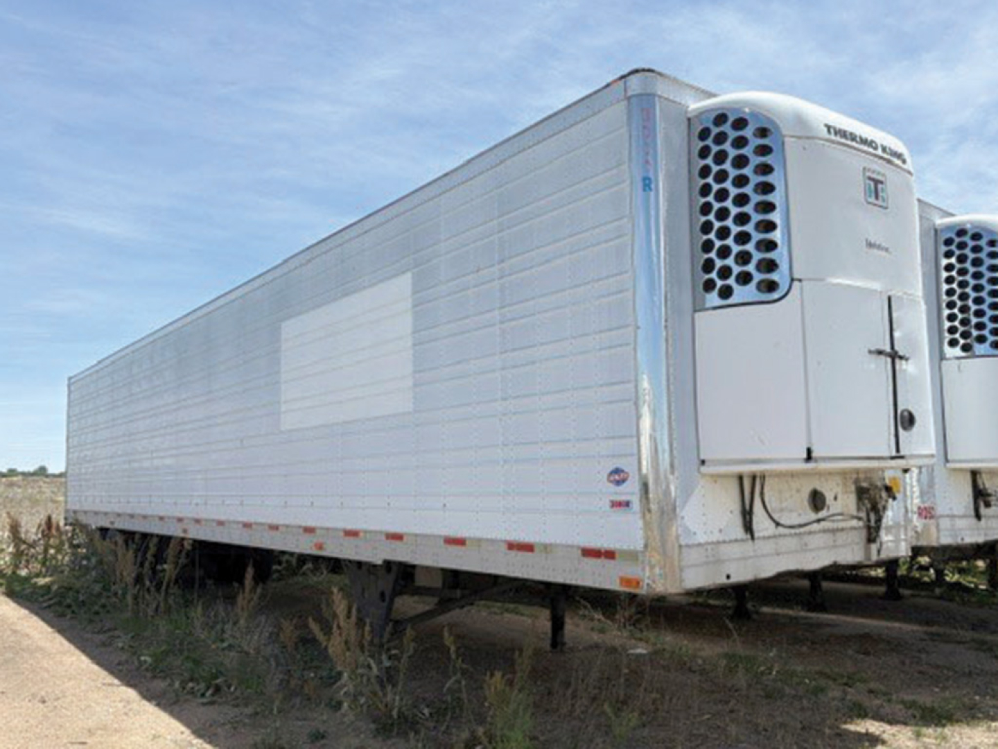 Trailer showing Thermo King reefer unit at the front, side panel with light reflection, utility 3000R trailer in yard.