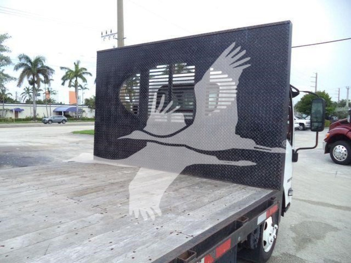 Truck bed and flatbed with decorative eagle graphic on back of Isuzu NPRR flatbed truck.