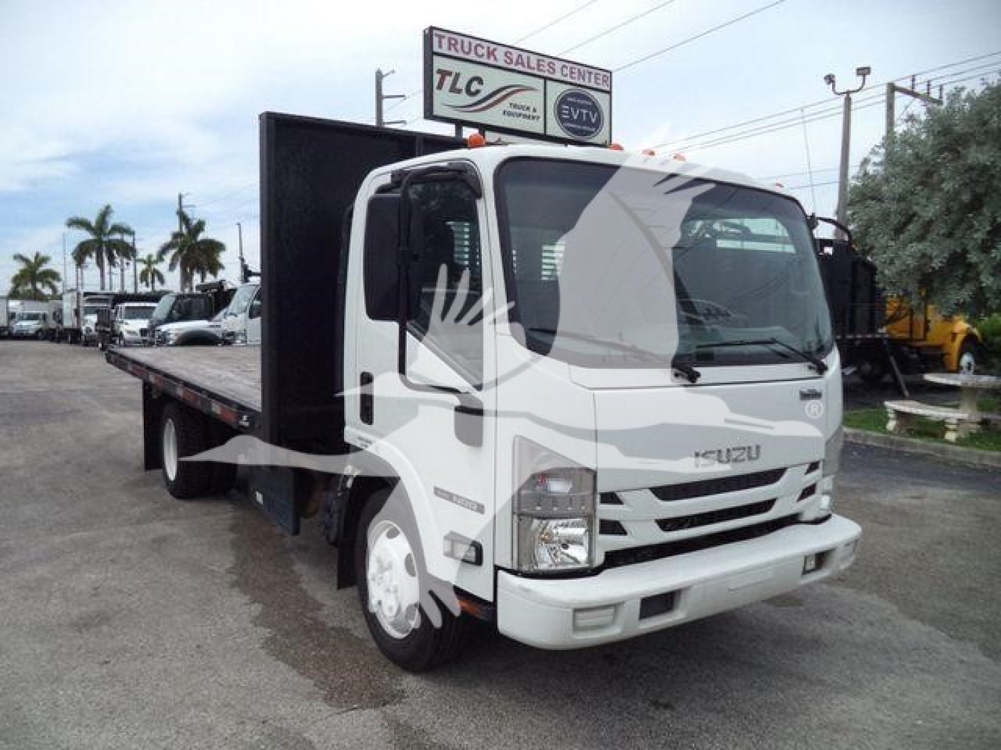 Isuzu NPR flatbed truck in service showing cab and flatbed bed with white exterior and ETC details visible.