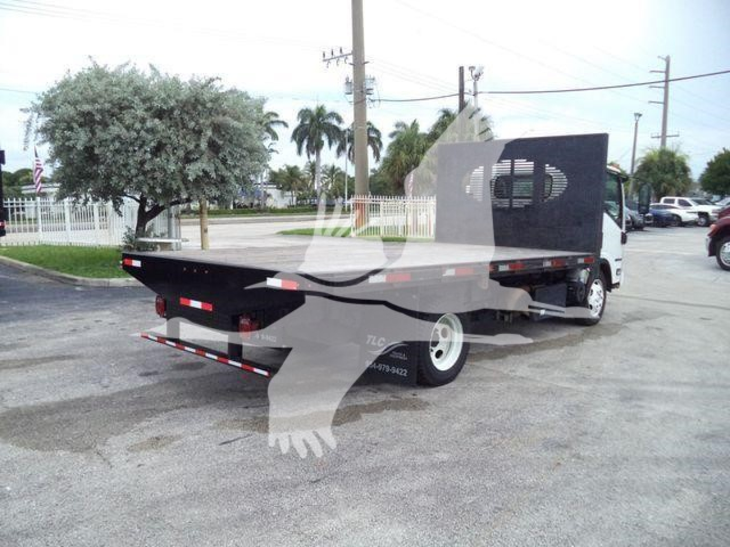 Isuzu NRR flatbed truck showing rear and driver side with utility box and dual rear wheels.