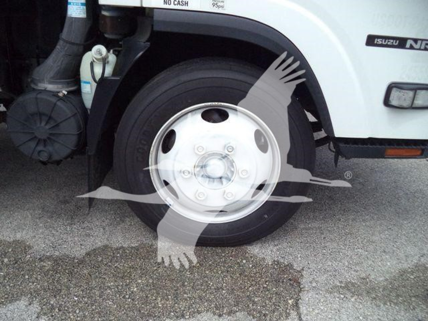 Isuzu NPR truck front wheel and fender with tire and wheel cover visible.