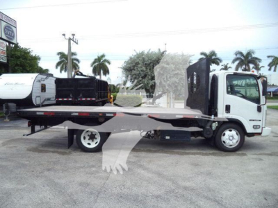 Isuzu NPR/NRR flatbed truck side view showing flatbed and wheel, cab white, some equipment in bed.