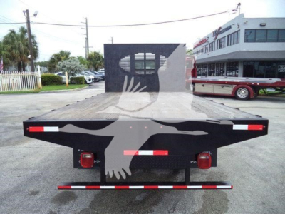 Isuzu NRR flatbed truck rear view showing flatbed with black steel and red/white reflective markings, tail lights, and hitch plate.