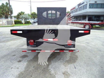 Isuzu NPRR flatbed truck rear view showing taillights and mudflap with metal deck in a dealership lot.