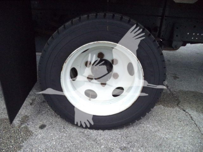 Isuzu NPRR truck wheel and tire mounted on white steel rim under flatbed, partial chassis visible.