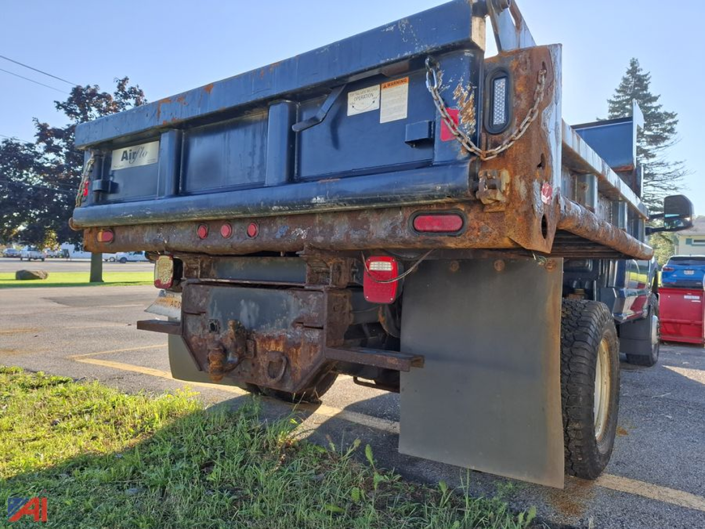 Dump truck bed and rear view showing rusty frame, plow mount, and taillights with mudflaps visible.
