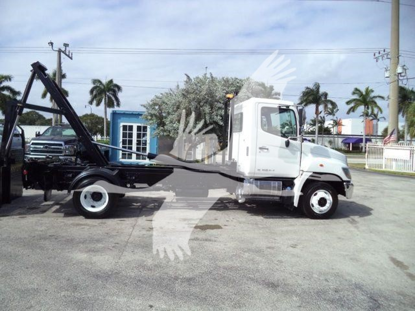 2017 Hino 258Lp hooklift truck side view showing truck cab and hooklift arm, VIN 5PVNJ8JNXH4S52712