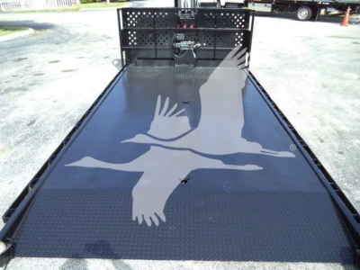 Flatbed with black metal deck and rear ramp on a used 2017 Hino 258LP hooklift truck