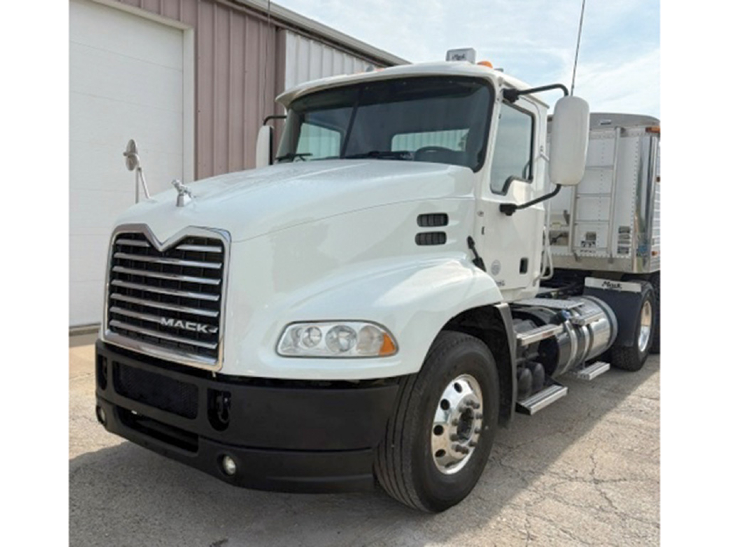 White 2015 Mack CXU613 daycab truck with large grille, dual rear wheels, side fuel tanks, cab mirrors, and headlights visible.