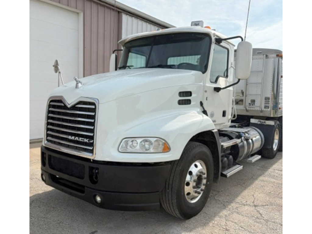 White 2015 Mack CXU613 daycab truck with large grille, dual rear wheels, side fuel tanks, cab mirrors, and headlights visible.