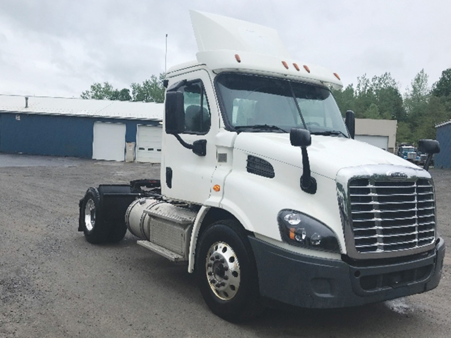 Tractor truck cab in white 2018 Freightliner Cascadia113 semi-truck with chrome grille and large side mirrors.