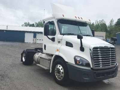 Tractor truck cab in white 2018 Freightliner Cascadia113 semi-truck with chrome grille and large side mirrors.