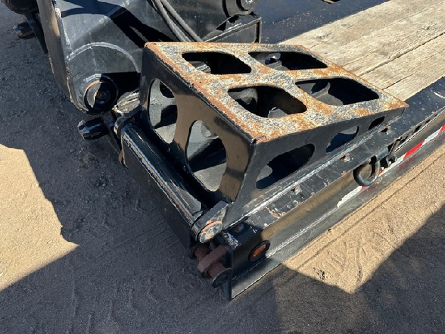 Lowboy trailer rear showing rusted toolbox on deck and loading ramps with attachment hardware.