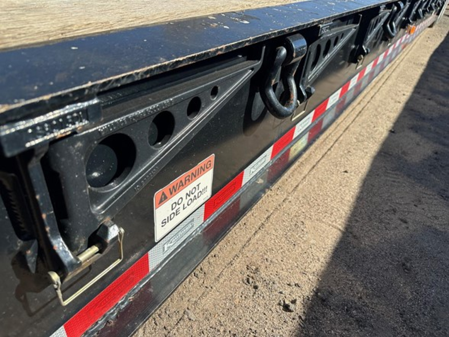 Trailer side view showing warning label and mounting hardware on Kaufman lowboy pony motor trailer deck.
