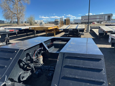 Lowboy trailer hitch area and pony motor compartment visible on 2022 Kaufman lowboy trailer, metal decking, wiring and hydraulic components in view.