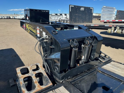 Lowboy trailer pony motor unit with hydraulic cylinders and control linkage, black metallic finish, Kaufman logo on side, flatbed trailer in background.