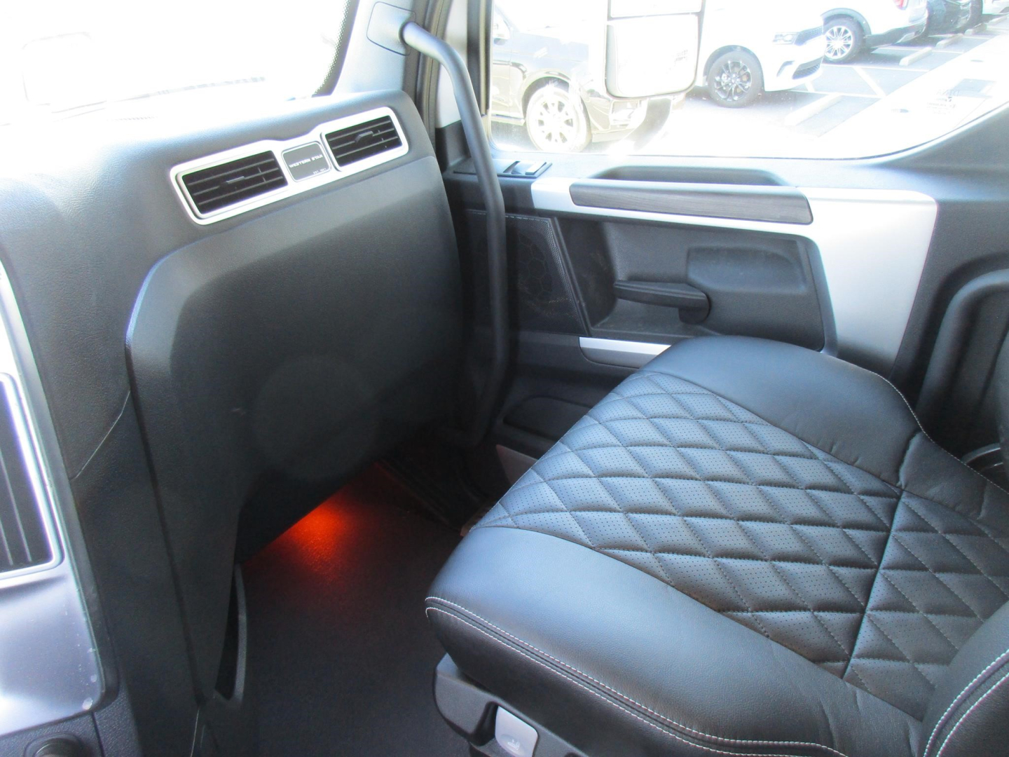 2027 Western Star 47X cab interior showing front passenger seat with diamond stitching, dashboard vents, and orange under-dash lighting.