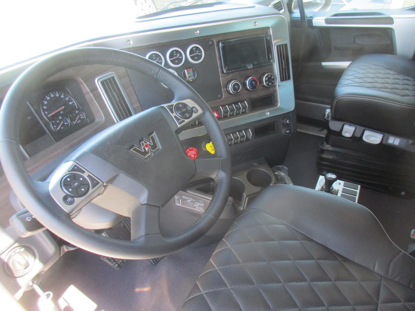 Western Star 47X truck interior showing steering wheel with W emblem, instrument cluster, large center touchscreen, climate controls, and diamond-stitched seat.