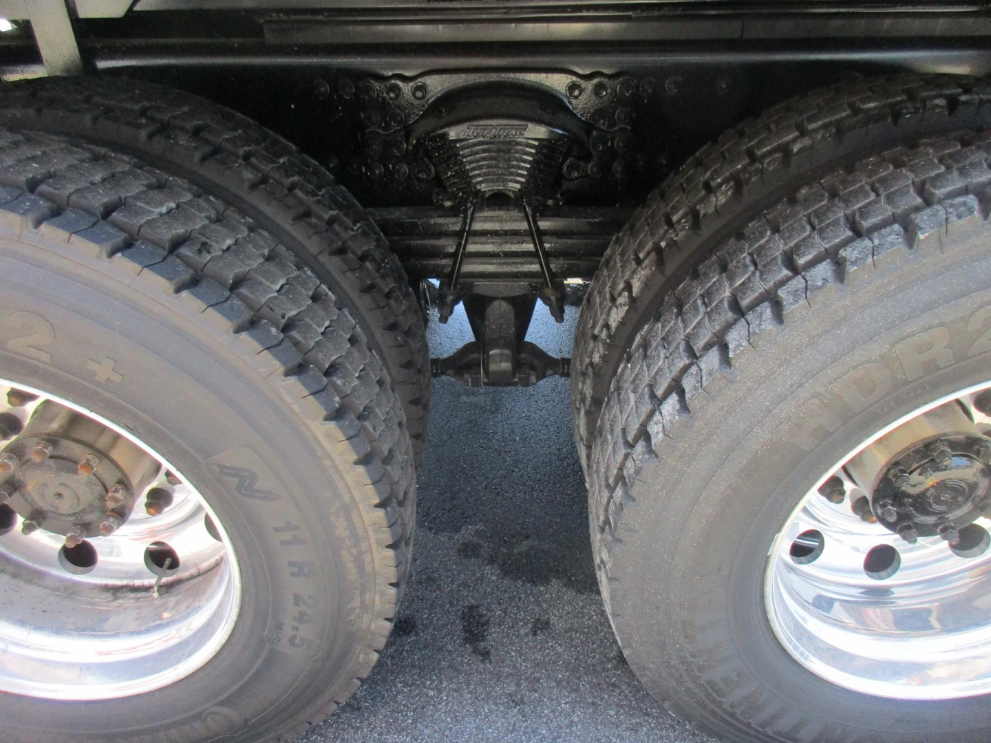 Two rear wheels of a Western Star 47X dump truck showing suspension and driveline components between the dual tires.
