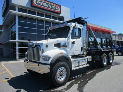 Dump truck in front of a dealership showing Western Star 47X cab and Ram dump bed with chrome fuel tanks